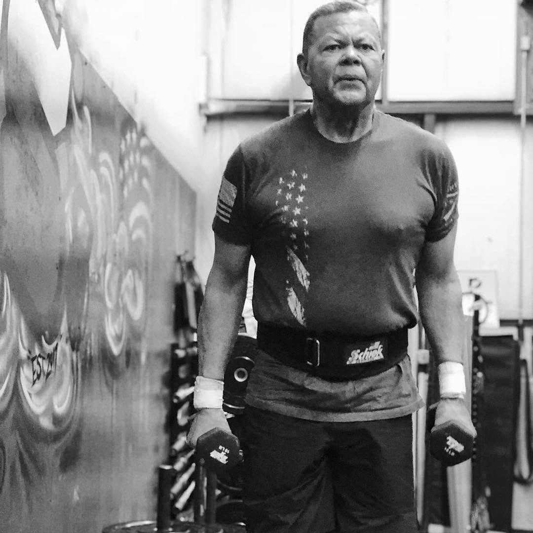 An older masters athlete mid-workout, dumbbells in hand