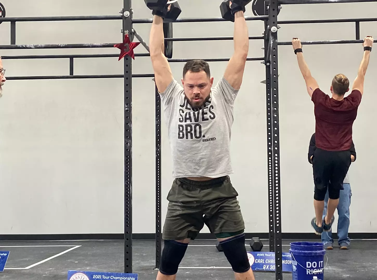 A masters athlete catching his breath, kneeling at the barbell
